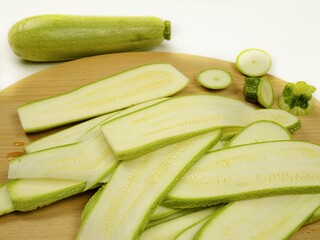 Slices of the fresh raw zucchini  are on a wooden cutting board
