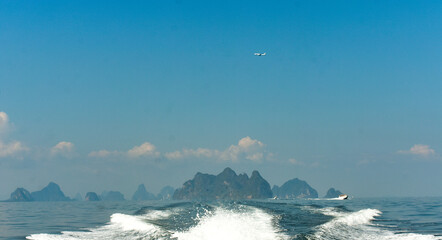 Airplane flying over a tropical seascape with islands and boats in Phuket. 