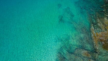 Aerial view of crystal clear turquoise water and rocky coastline in thailand