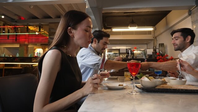 Focusing beautiful woman tasting main course tasty at delicious chef table cuisine with friends taking food together at back side. Theme of celebrating with couple or friend at restaurant. Vinosity. - Powered by Adobe