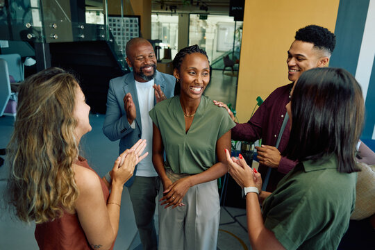 Group of diverse coworkers applauding black businesswoman in office during daytime