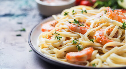 Italian pasta fettuccine in a creamy sauce with shrimp on a plate, close-up.