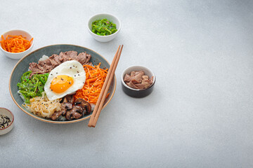 Bibimbap, authentic korean dish with a steamed rice topped with fried egg, beef, colorful...