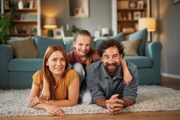 A family of three is having fun in their living room, with a child happily sitting on the shoulders of a parent. They are smiling, conveying joy and connection in a comfortable space.