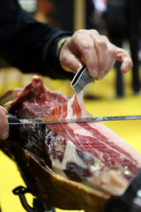 experto en cortar jamón cortando una loncha de un jamón ibérico con un cuchillo de corte y...