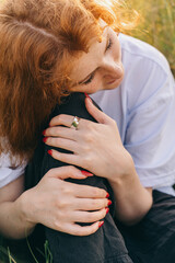 Naklejka premium A young woman sits with her head on her knees. Sad mood. Depressive state. Loneliness. Caucasian appearance girl is fair-skinned. Natural landscape.