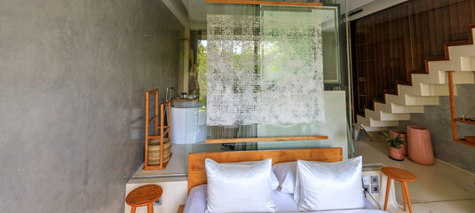 Bedroom with a white bed and pillows, a white curtain, and a wooden stool