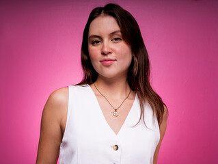 Fototapeta premium Confident Young Woman in Sleeveless Blouse against Pink Studio Background