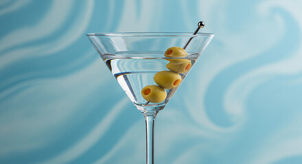 ''A classic martini cocktail with four green olives on a cocktail pick, served in a sleek glass against a soft blue swirled bac...
