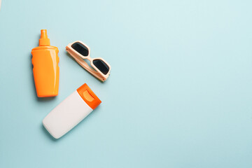 Sunscreen, sun cream and sunglasses on blue background.