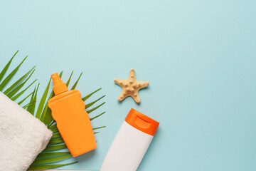 Sunscreen, towel and sunglasses on blue background.