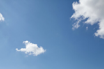 Clear blue sky with fluffy white clouds scattered across the horizon, creating a serene atmosphere, ideal for backgrounds or design projects with copy space