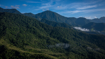 Fototapeta premium Aerial view of a mountainous and preserved region of the Atlantic Forest, a tropical rainforest in Rio de Janeiro, Brazil. The beauty and biodiversity are the highlights.