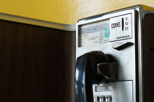 An Antique Coin Operated Payphone on a Yellow Wall