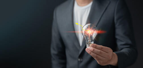 A businessman in a suit holding a glowing light bulb with a financial stock chart and arrow graphic inside. creative thinking, startup ideas, business growth, financial strategy, and market success.