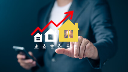 Businessman touching a glowing house icon with an upward red arrow growth in real estate investment and housing market trends. Modern concept of property investment, real estate financial success.