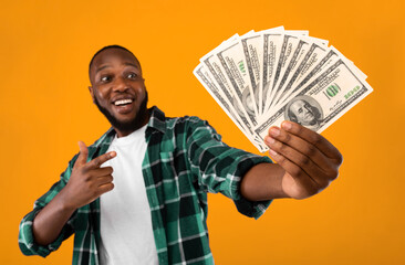 Happy Black Man Holding Money Cash Pointing Finger At Dollar Banknotes In His Hand Standing Over...