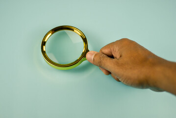Hand holding a magnifying glass, focusing on the task at hand.