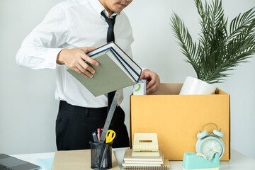 Business man employee packing notebook and picking up personal belongings into brown cardboard box