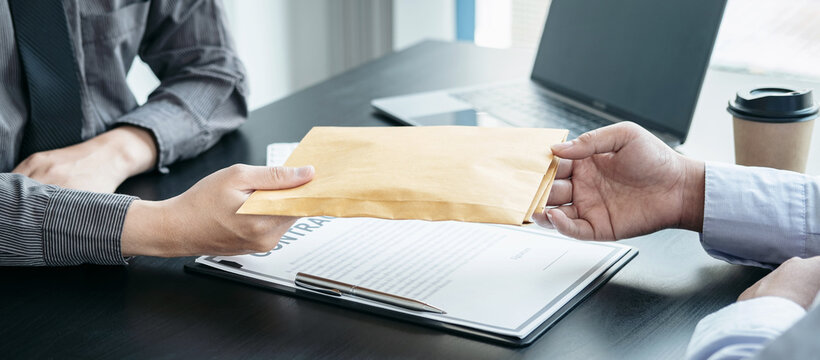 Businessman accepting a bribe money in the envelope from businesswoman after signing on the contract to joint