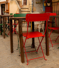 Colorful iron chairs and wooden tables with stairs and vases in the background
