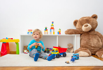 Sweet happy child boy having fun playing with colorful toys on the floor, at home