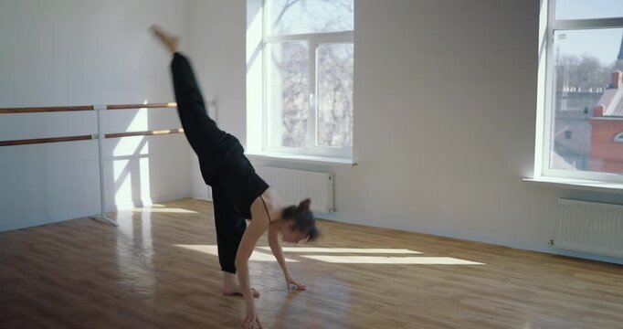 Girl in a black dance costume performs graceful movements during her contemporary dance with elements of Modern Java on the floor in the Dance Studio