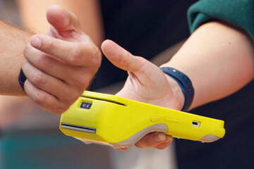 A customer completing a contactless payment using a wearable device at an outdoor event, paying by attaching a smartwatch to a payment terminal. The interaction highlights modern technology.