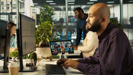 Fototapeta premium Worker in office talking with colleagues during internet videocall. Employee at work discussing with business partners during remote teleconference meeting, analyzing metrics, camera B