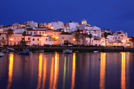 Portugal, Algarve Region, Ferragudo. Picturesque fishing town reflected on the bay after dusk.