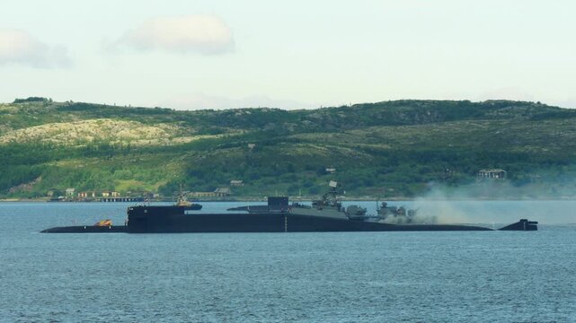 An anti-submarine frigate sails past an anchored nuclear submarine in the Kola Bay during the annual Navy Day holiday.
nuclear-powered submarine