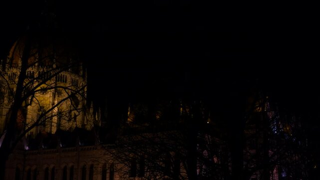 Hungarian parliament building emerging from darkness at night. Night darkness gradually giving way to golden illumination, revealing stunning neo-gothic hungarian parliament building
