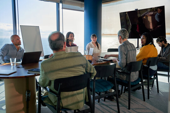 Group of business people sitting at modern office with views, gathered for a meeting, discussing strategy and analyzing workflow and new ideas.