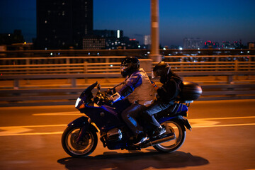 Motorcycle ride through the city at night. A man driving a motorcycle. Woman on a motorcycle looking at her smartphone while riding. High quality photo