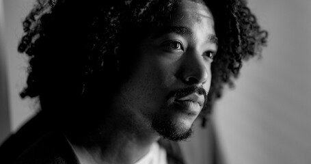 Black and white portrait of a thoughtful young african-american man with curly hair looking away