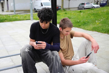 Two teenage guys with smartphones outside, friends coomunication concept, life online