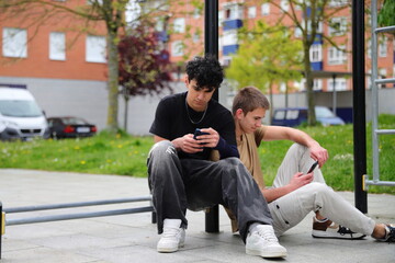 Two teenage guys with smartphones outside, friends coomunication concept, life online