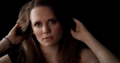 Studio portrait of a beautiful young woman playing with her hair on a black background