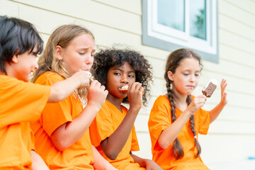 Group of Happy diversity children boy and girl kids eating ice cream together at summer camp. School student enjoy and fun outdoor lifestyle active playing outside classroom and exercising at kid park