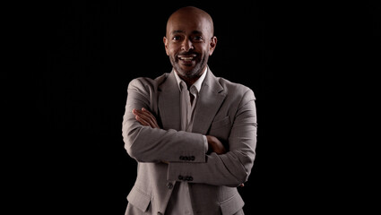Portrait of confident african american businessman smiling with crossed arms on black background