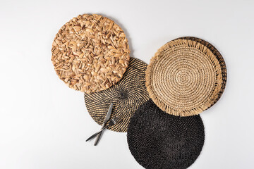 Top View of Assorted Woven Placemats, Detailed Display of Diverse Textures from Tight Black Weave to Natural Straw, Elegantly Set on Pristine White Background with Sleek Stainless Steel Cutlery.
