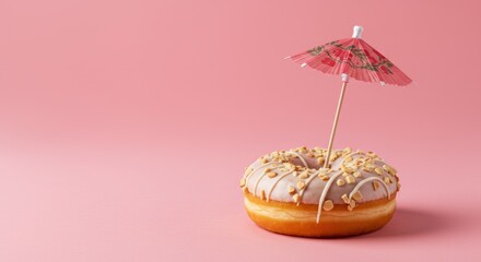 Delicious donut topped with peanuts and a mini umbrella on a bright pink background