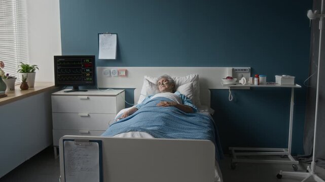 Elderly woman with oxygen tubes and pulsometer lying in bed, sleeping peacefully while monitor with her heart rate working in background