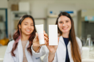 Latina scientists showing skincare product and packaging in a cosmetic laboratory
