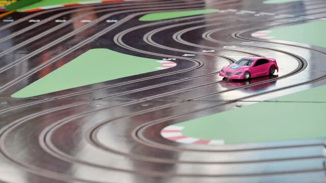 White and pink toy cars competing on a slot car track during a sports day, providing entertainment and excitement.