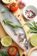 Fresh raw seabass with spices on white wooden table, flat lay. Fish and seafood delicacies