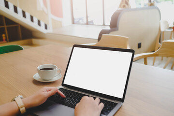 A person's hands typing on a laptop with a blank white screen in a family-friendly coworking space or kids' cafe, illustrating a modern work-life concept.
