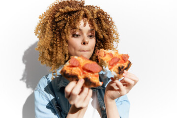 Young woman enjoying delicious pepperoni pizza, showcasing excitement and joy, with curly hair against a clean white background, emphasizing a vibrant food lifestyle