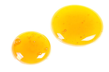 Two drops of golden liquid with bubbles isolated on black background