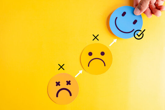 Blue smile face selected above sad expressions on yellow background, emotional clarity, mental shift, and wellbeing strategy for positive mindset and life balance.